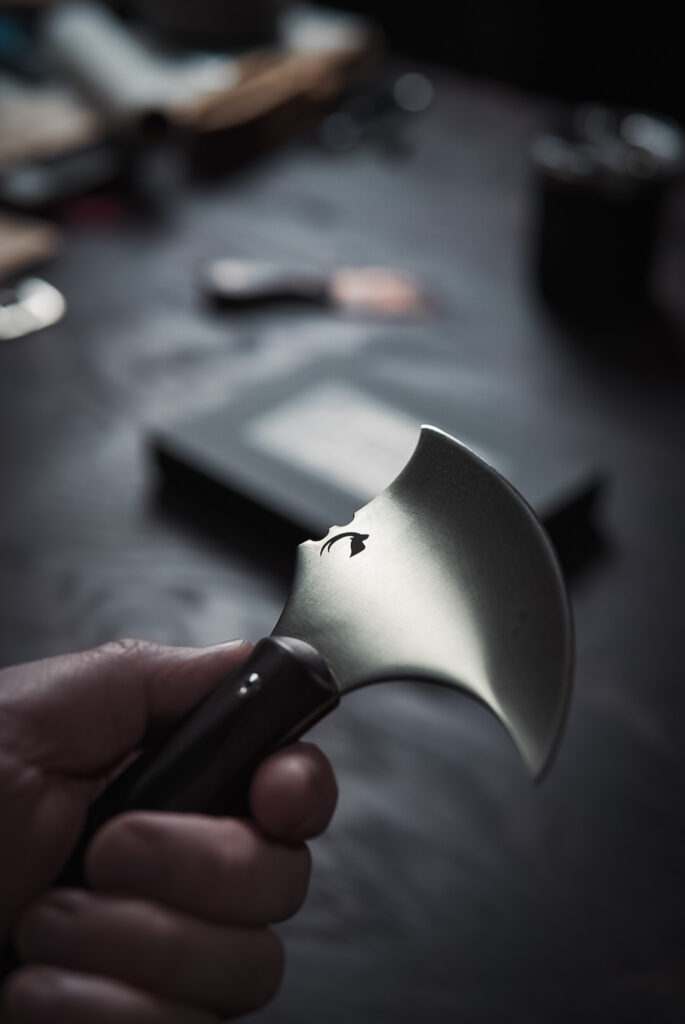 A leather pattern knife, dramatically lit, held in hand